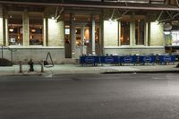 an empty city street at night with a sign showing parking places, and a building behind it