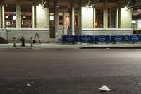 an empty city street at night with a sign showing parking places, and a building behind it