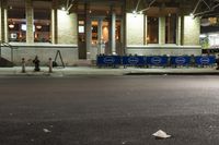 an empty city street at night with a sign showing parking places, and a building behind it