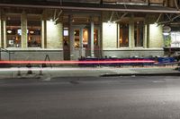 an empty city street at night with a sign showing parking places, and a building behind it