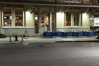 an empty city street at night with a sign showing parking places, and a building behind it
