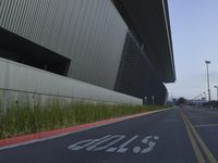 a paved empty street with a large building in the background and signs on it saying stop