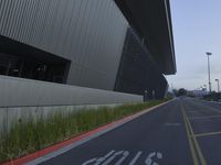 a paved empty street with a large building in the background and signs on it saying stop