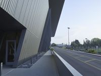 a paved empty street with a large building in the background and signs on it saying stop