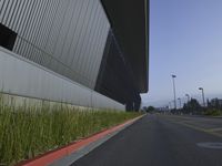 a paved empty street with a large building in the background and signs on it saying stop