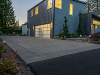 a gray and blue two story house in the evening light by some trees and plants