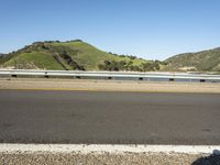 a road and a body of water near a bridge in the background of mountains and water