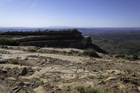 a person is riding on a motorcycle on a rock road in a canyon with an area that has a mountain range in the distance