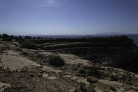 a person is riding on a motorcycle on a rock road in a canyon with an area that has a mountain range in the distance