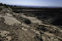 a person is riding on a motorcycle on a rock road in a canyon with an area that has a mountain range in the distance