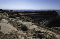 a person is riding on a motorcycle on a rock road in a canyon with an area that has a mountain range in the distance