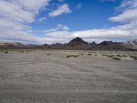 a view of the desert area with mountains in the background and a red van parked on the side