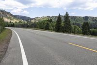 there is an empty highway on the mountain side with mountains in the background during daytime