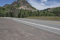 this is a picture of an empty road in the mountains with mountains in the background