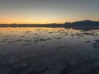 a view of an ocean during sunset in the beach area at low tide, near a beach resort