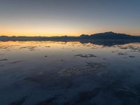 a view of an ocean during sunset in the beach area at low tide, near a beach resort