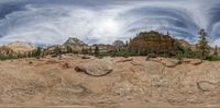 an open area with rocks, trees and boulders under a cloudy sky sky as seen through a fish - eye lens