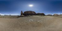 a desert landscape with a fence, rocks and a sun in the sky above it