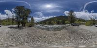 a landscape showing a river and mountain scenery with rocks and gravel around the body of water