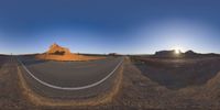 the panoramic image shows some sort of desert with rocks in the distance and on each end a long path is surrounded by grass