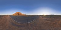 the panoramic image shows some sort of desert with rocks in the distance and on each end a long path is surrounded by grass