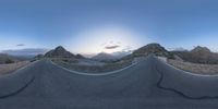 the panoramic image shows some sort of desert with rocks in the distance and on each end a long path is surrounded by grass