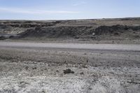 a dirt road is surrounded by some hills and desert like terrain as the vehicle sits on it