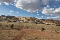 a landscape image of a lone man and road going through the desert with rolling clouds