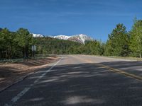 an empty road with lots of trees in the background in the wild region of colorado