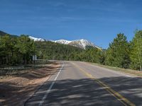 an empty road with lots of trees in the background in the wild region of colorado