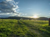 a lone country road is in the countryside area with mountains on both sides and barbed fence between the two sides