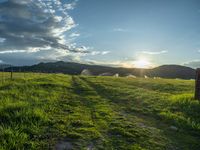 a lone country road is in the countryside area with mountains on both sides and barbed fence between the two sides