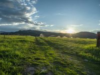 a lone country road is in the countryside area with mountains on both sides and barbed fence between the two sides