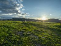 a lone country road is in the countryside area with mountains on both sides and barbed fence between the two sides