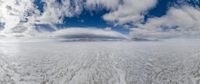 a white sand desert with a mountain in the distance and a large cloud above it