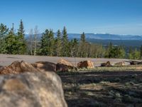 the mountains are visible in the distance from this wide, empty road, overlooking a wide landscape and forest