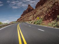 a road that is paved and wide with yellow lines in front of a mountain range