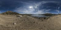 360 lens image of a beautiful landscape and a body of water surrounded by boulders, rocks, and trees