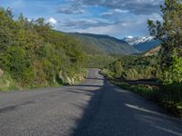 the road winds up on the mountainside on a sunny day with beautiful clouds and trees