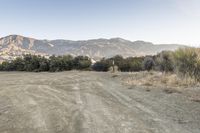 a dirt road running next to a large mountain side with mountains in the background,