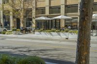 people sit outside an outdoor restaurant with umbrellas in the sunshine over the tables and chairs