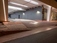 an empty parking garage at night with multiple light fixtures on the side of the building