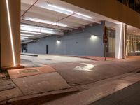 an empty parking garage at night with multiple light fixtures on the side of the building