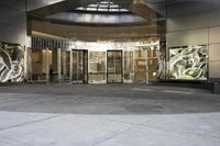 the entrance to a large building with glass doors in it and an outside area that has glass wall panels