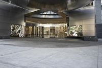 the entrance to a large building with glass doors in it and an outside area that has glass wall panels
