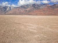 an image of a barren desert field with mountains in the background and blue sky above