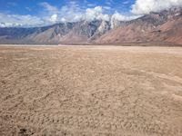 an image of a barren desert field with mountains in the background and blue sky above