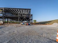 a picture of a building being built on a field near a forest in the background