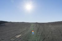 there is a rainbow shaped kite on the sand covered hill in the middle of the field