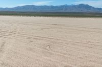 a person riding their bike across an empty desert field area with mountains in the background